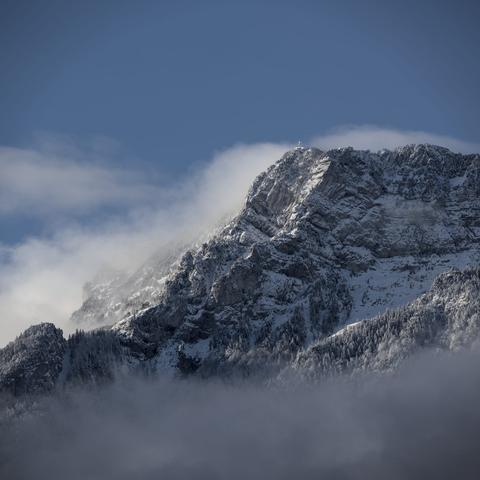 Photo couleur d'une montagne juste après la neige. Quelques écharpes de nuage cachent quelques rochers.
