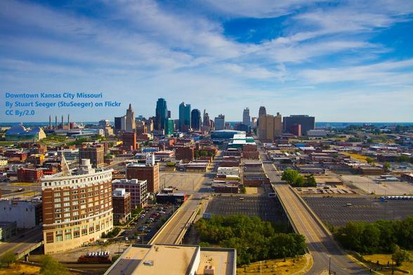 Photo of Downtown Kansas City, as viewed from the Sheraton Hotel. Lots of car parking, plenty of low-rise buildings, but also some multi-storey buildings in the near foreground, with the much taller skyscrapers and other tall buildings of the city centre further away.