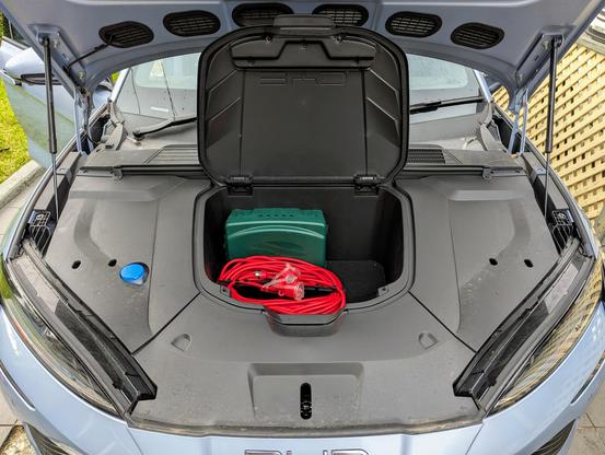 Photo of the open frunk of a BYD Seal electric car. Inside are a very long mains extension cable, and a green box.