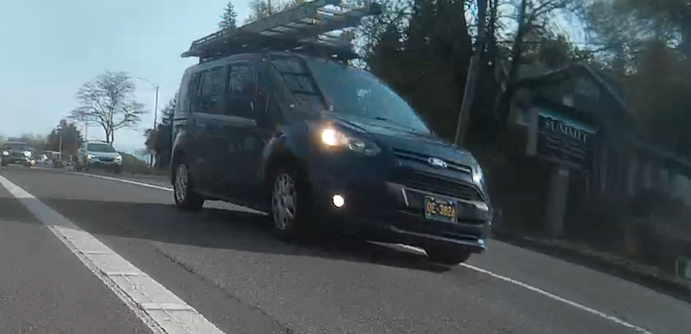 dark ford transit van with ladders on top, license plate is yellow letters on dark background OE-3824 (I think Oregon PW)