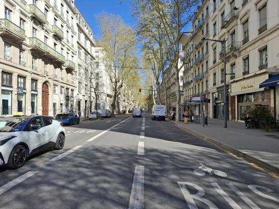 Autre vue de l'avenue Foch en avançant de 300m vers le sud. Axe vide et deux voies de bus. Un taxi attend sur la voie nord-sud.