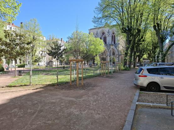 Place puvis de Chavanne qui est un square avec des pelouses et des bancs. La place est aussi arborée. En arrière plan une église a la façade imposante.