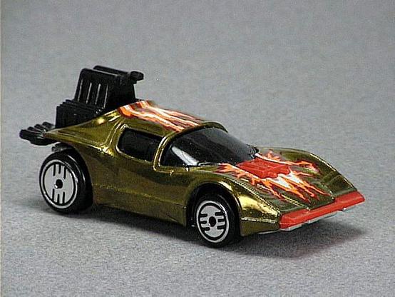 Released in 1984, Metal Flake Gold Flame Runner of 1984 Hot Wheels with Ultra Hot wheels. Notes: Concept car with exposed black plastic engine in back, red plastic front bumper and hood ornament. Tampo: White, orange and dark red flame on top. Packaging: 1984 Blister. Metal Body, Metal Base. Made in Hong Kong. Scarcity: 4/10