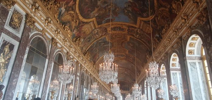 Hall of mirrors in versailles. You see the hugely and gold decorated ceiling as well as lots of chandeliers.