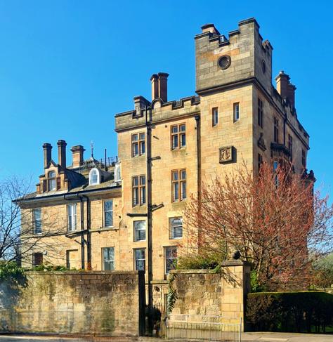 A large and imposong Victorian blonde sandstone mansion.