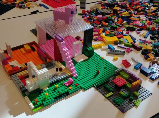 ein lego buerohaus mit einem gluecksschwein und blumenwiese davor