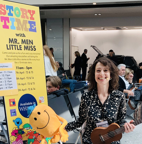 Me in the middle of an airport terminal with a sign which says storytime and it’s branded on mr men and little Miss. I’m holding me tickle plushie