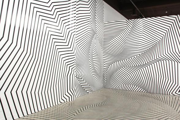 Two white walls covered in black tape lines creating jagged and curving indentations, and reflected on the mirrored floor.
