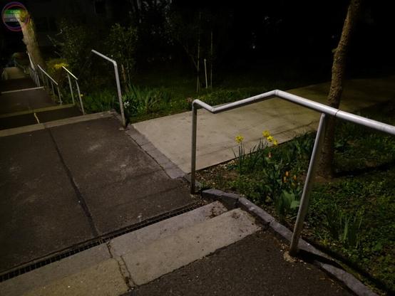 Fußweg in Wohnsiedlung mit kurzen Stufenabschnitten, das Geländer läuft mit und hat im Niveauwechsel keine Zwischenstütze