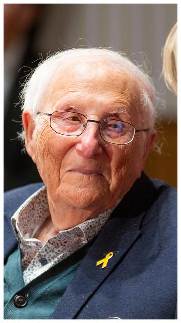 KZ-Überlebender Albrecht Weinberg als hochkant Portraifoto. 
Ein hundert Jahre alter Mann mit Falten, Altersflecken, Brille und weißem schütteren Haar grinst in einem Gespräch mit einem Jugendlichen in die Kamera. Der Jugendliche ist nicht zu sehen.
Um Das Bild ist ein kleiner weißer Rahmen.