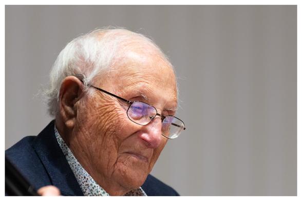 KZ-Überlebender Albrecht Weinberg als querformat Portraifoto. 
Ein hundert Jahre alter Mann mit Falten, Altersflecken, Brille und weißem schütteren Haar grinst mit dem Kopf nach unten gerichtet
Um Das Bild ist ein kleiner weißer Rahmen.