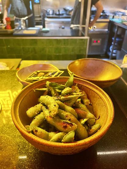 Edamame served on top of a counter with reflected neons