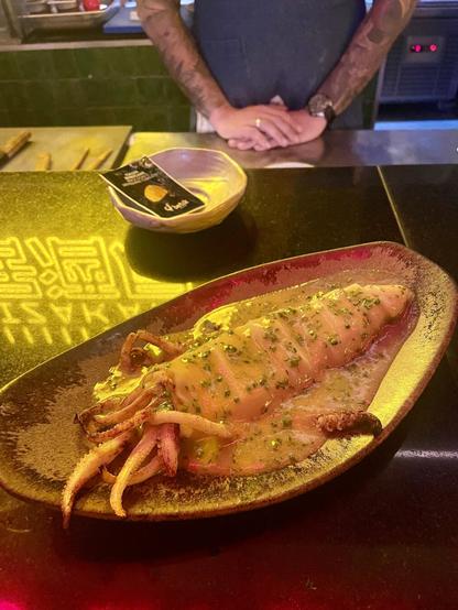Buttery sauce squid served on top of a counter with reflected neons