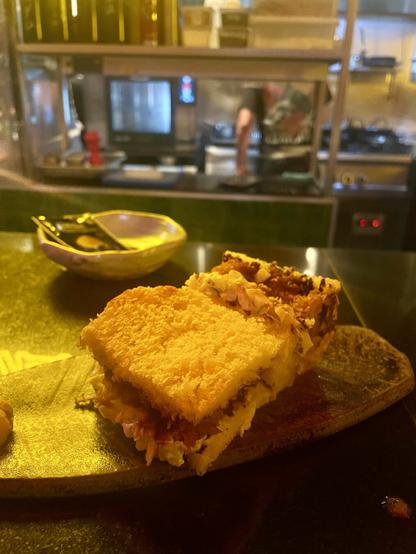Katsu sando served on top of a counter with reflected neons