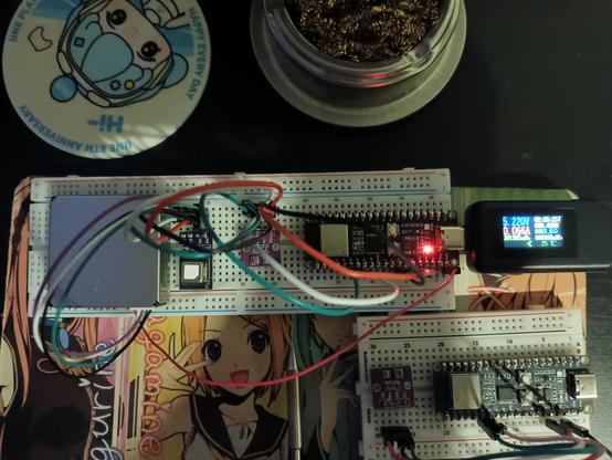 A breadboard with various sensors and a microcomputer. A USB-C power measurement tool is also visible.