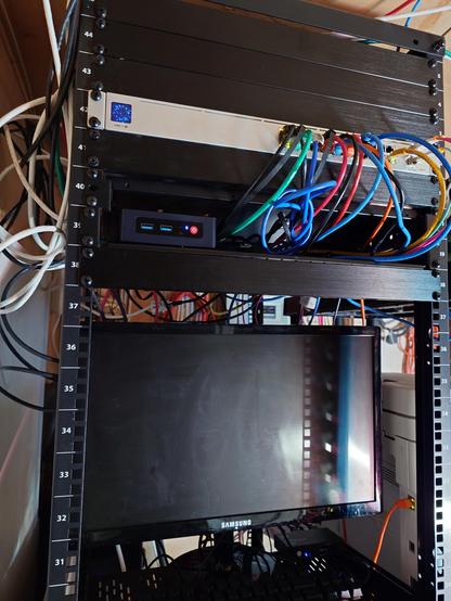 Rack showing messy wires, a screen, and to one side in the corner a little mini computer