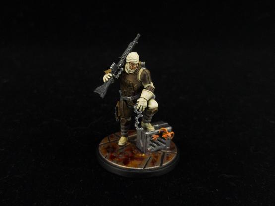 Painted Dengar miniature from Star Wars Shatterpoint in classic ESB colors (brown armor and white toilet paper). Leaning on a box containing an orange alien from the same species as Salacious Crumb.