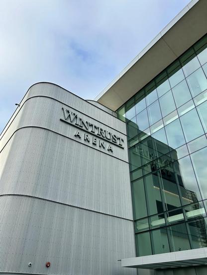 Picture of a building with corrugated metal siding to the left and large windows to the right, with text reading “Wintrust Arena”.
