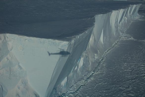 An iceberg corner with the shadow of a helicopter on it. HOw big are Antarctic bergs? Really big