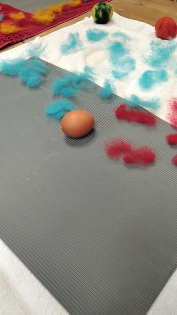 Auf dem Bild ist ein ausgeblasenes Ei und Filz zu sehen.