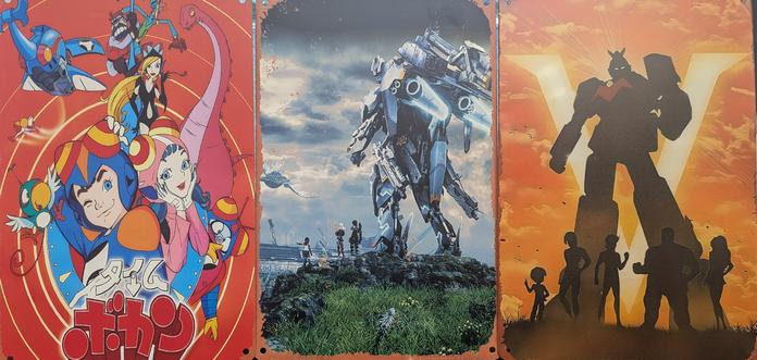 Three metal prints arranged as a triptych: Time Bokan, with the characters prominent in the centre of a red background, Xenoblade Chronicles X, with the box art of a skell towering on a lookout with characters beside it, Voltes V, with a silhouette of the mecha and silhouettes of the characters.