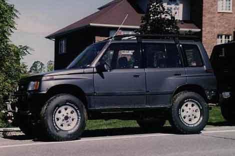 1993 Suzuki Sidekick (4 door) in grey, lifted 3" and 33x9.5x15 tires on original JLX spec wheels (not recommended wheel fitment - too narrow for tires).