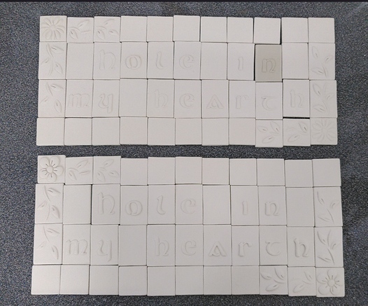 2 identical Mosaic tiles assembled. Message is Hole in my hearth. Bisqueware stage. Waiting to be glazed.