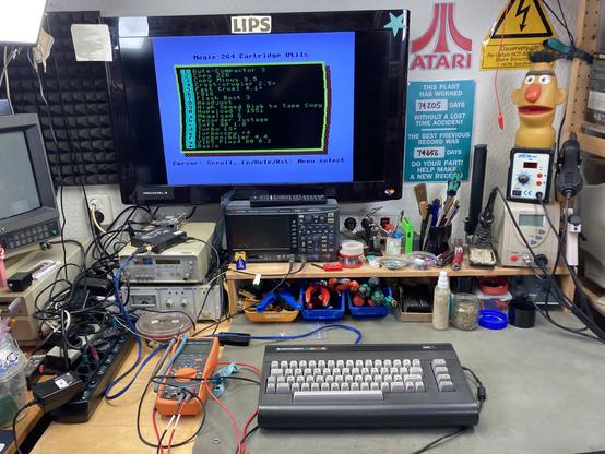 My Commodore 16 on my desk with a wavy menu showing on the connected screen that lists some software accessible from the C264 Magic Cart that is plugged into the cartridge port.