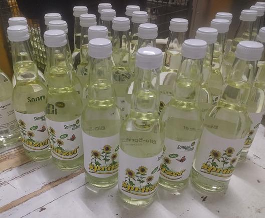 Viele kleine Glasflaschen mit Sonnenblumen und der Aufschrift "Spritzer" auf dem Etikett.