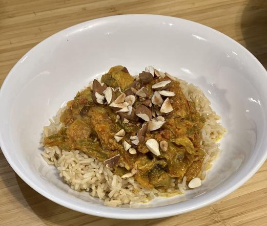 A curry topped with toasted almonds on a bed of rice.