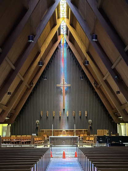 A cross at the front of the sanctuary illuminated by sunlight through a stained glass roof. Above statues of the disciples & the altar. Taken at All Saints Episcopal Church in Omaha, Nebraska by Jay C. Hammond . All rights reserved.