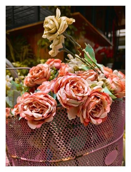 A close-up view of a pink wire basket overflowing with artificial roses.
