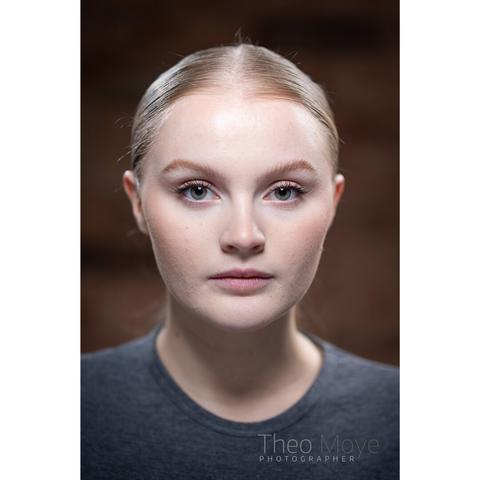 A young woman with her blonde hair tied back with high-contrast lighting