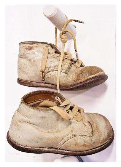 Antique children's shoes hanging from a hook.