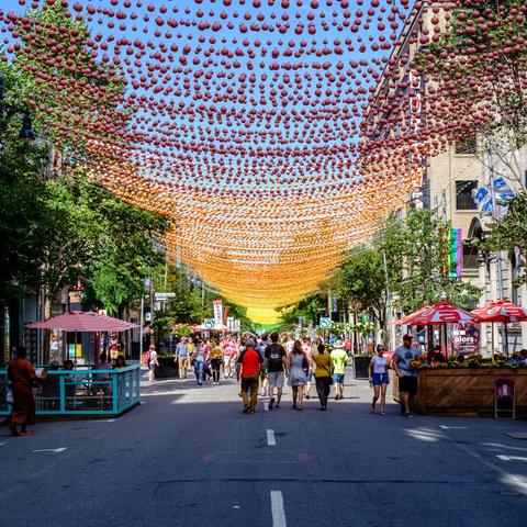 A pedestrian street with overhanging colour balls producing a rainbow colour gradient to then end of the street.