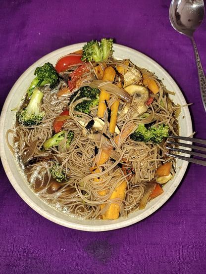 My dinner: carrots, broccoli, sugar snap peas, sweet potato, shallot, red peppers, mushroom and seaweed, with brown rice thread noodles and miso broth. Purple tablecloth.