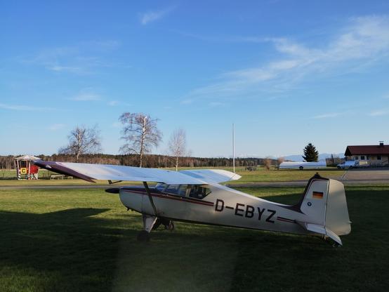Dirty aircraft parked in front of mountain panorama under a blue evening sky