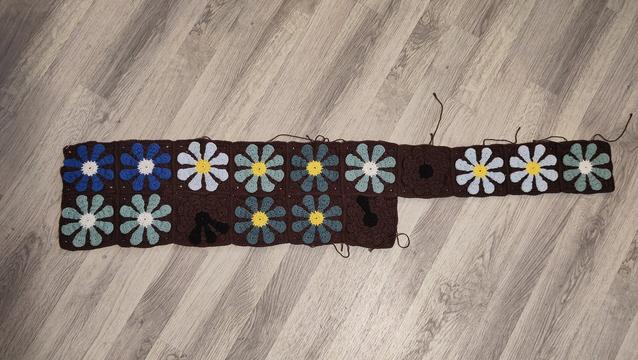 16 crocheted flower squares with brown backgrounds and different shades on the flowers.

1st row:
2 white center flowers with bright blue petals
Yellow center flower with light blue petals 
Yellow center flower with haze blue petals
Yellow center flower with petrol petals
White center flower with haze blue petals 
Black center flower with brown petals
2 yellow center flowers with light blue petals

2nd row:
2 white center flowers with haze blue petals
Black center flower with 3 black petals
2 yellow center flowers with petrol petals
Black center flower with 1 black petal.