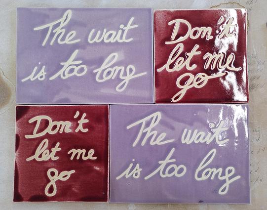 4 ceramic tiles displayed together. 2 are rectangle and light purple with handwritten "The wait was too long". 2 are square and red with handwritten "don't let me go".