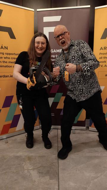 Me, posing with veteran game designer Tom Hall. I'm holding the literal chainsaw that was used as the template for the Doom chainsaw sprite. Tom is making an aggressive face with raised fists.