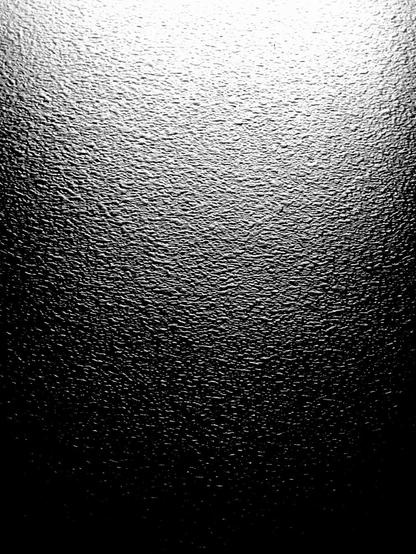 A mildly crumpled, desaturated surface texture fills the frame, lit bright white at the top and fading down to pitch black at the bottom.