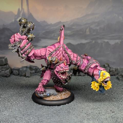 Pink sharkman holding a yellow and blue fish in one hand and a flail in the other