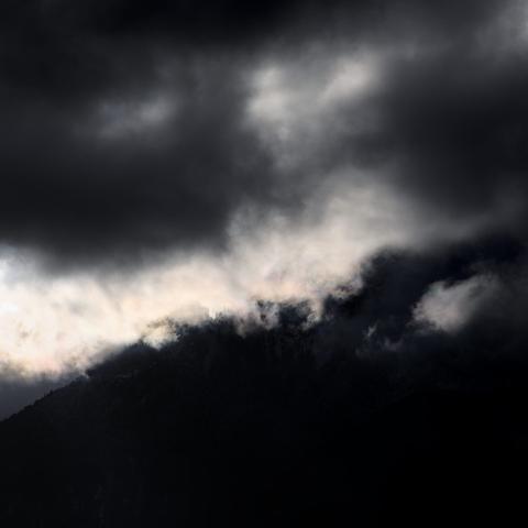 Photo d'une montagne quasiment entièrement cachée, on devine à peine une crête entre deux nuages.
