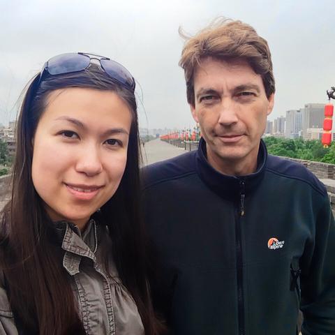Double selfie with a stretch of the city wall in the background, a row of red lanterns on the right, and a gray sky above.