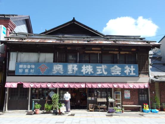A late 19th century Japanese building with a black roof, blue sign and open first floor.