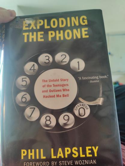 EXPLODING THE PHONE by Phil Lapsley, foreword by Steve Wozniak. The book cover has a graphic of all old rotary dial phone face. "The untold story of the teenagers and outlaws who hacked Ma Bell".