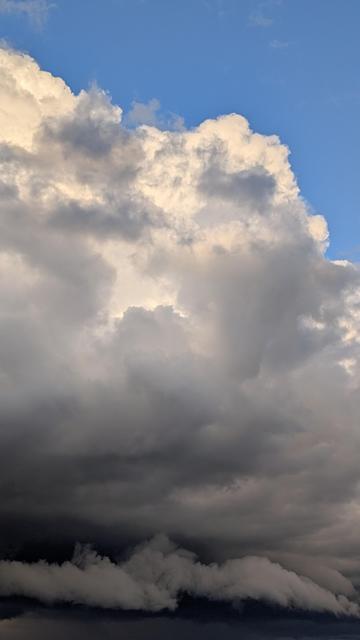 A dramatic section of the sky ranging from Blue with white clouds near the top to dark gray, stormy and swirling along the bottom.