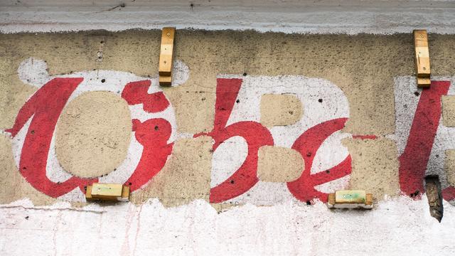 color photograph, landscape format. facade of a former furniture store. overlapping advertisements with the word “möbel”, red, white and brown.