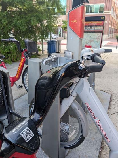 Two standard Capital Bikeshare bikes and one of the service's e-bikes, as seen at the CaBi dock by one entrance of the Court House Metro stop in Arlington.