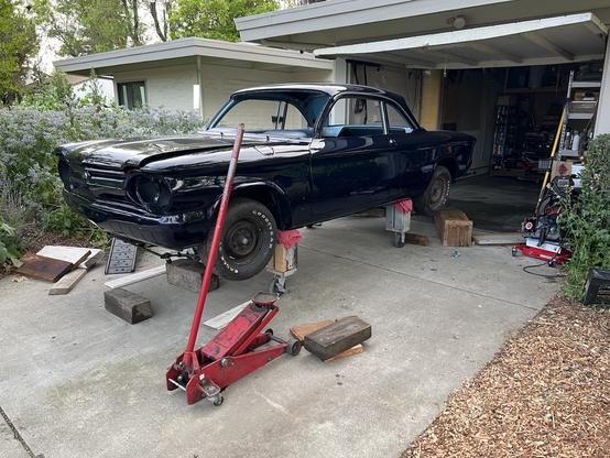 A shiny 1964 Corvair Monza on a tall wooden dolly.